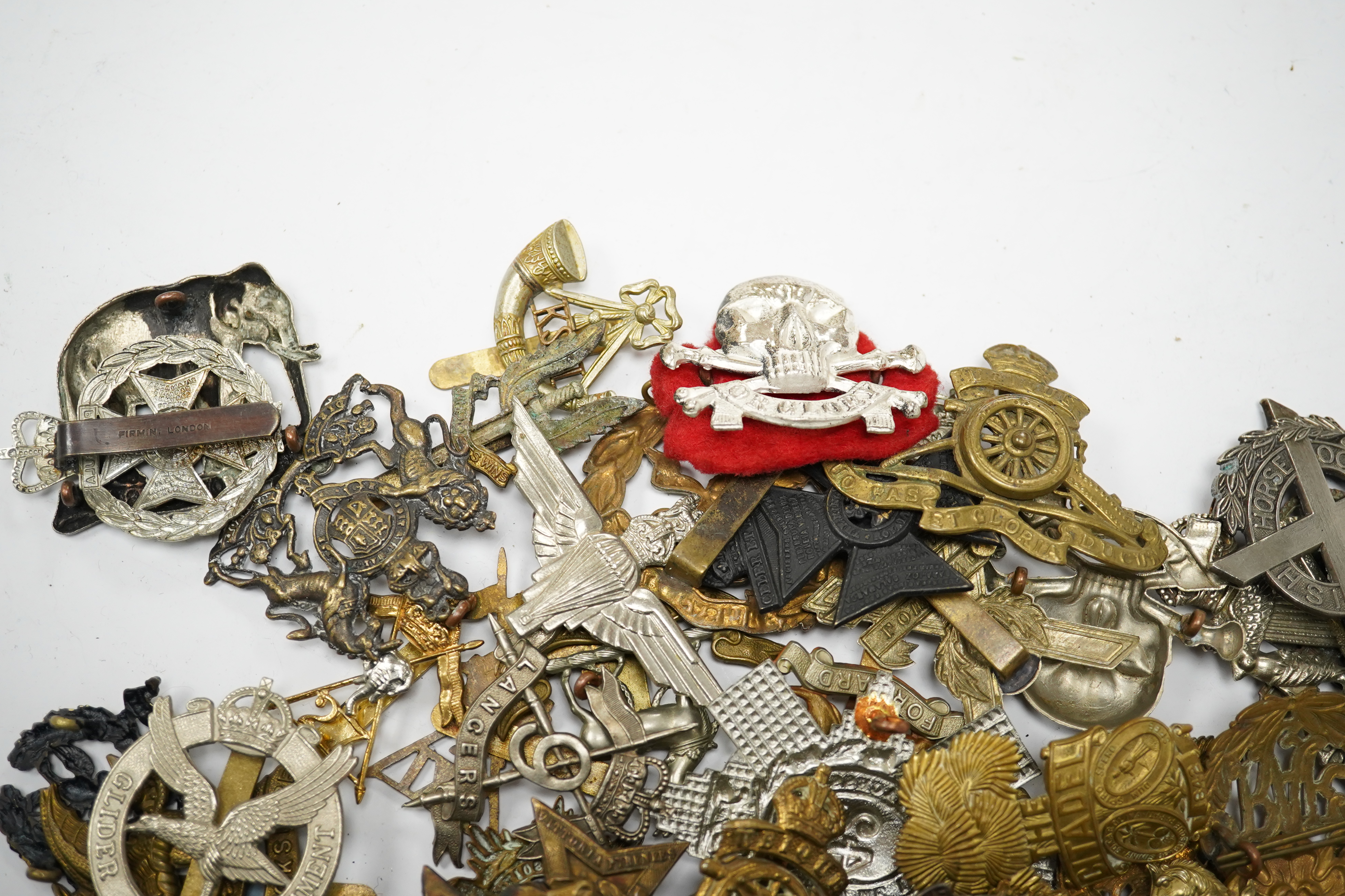 Sixty military cap badges, including; the Brecknockshire Regiment, the Royal Warwickshire Regiment, the South Lancashire Prince of Wales Volunteers, the Royal Artillery, the East Lancashire Regiment, the Glider Pilot Reg